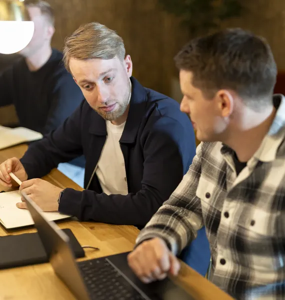 Twee collega's overleggen achter een laptop