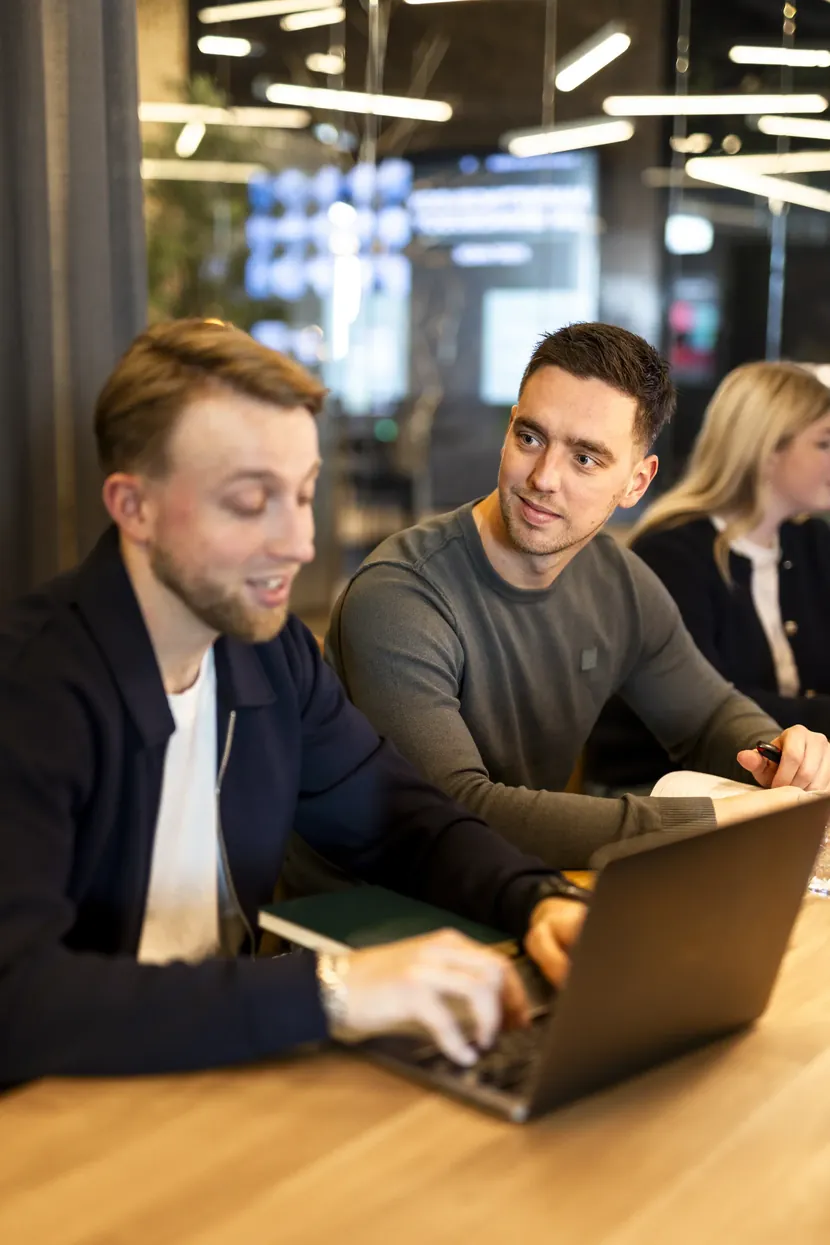 Twee collega's werken samen aan een laptop
