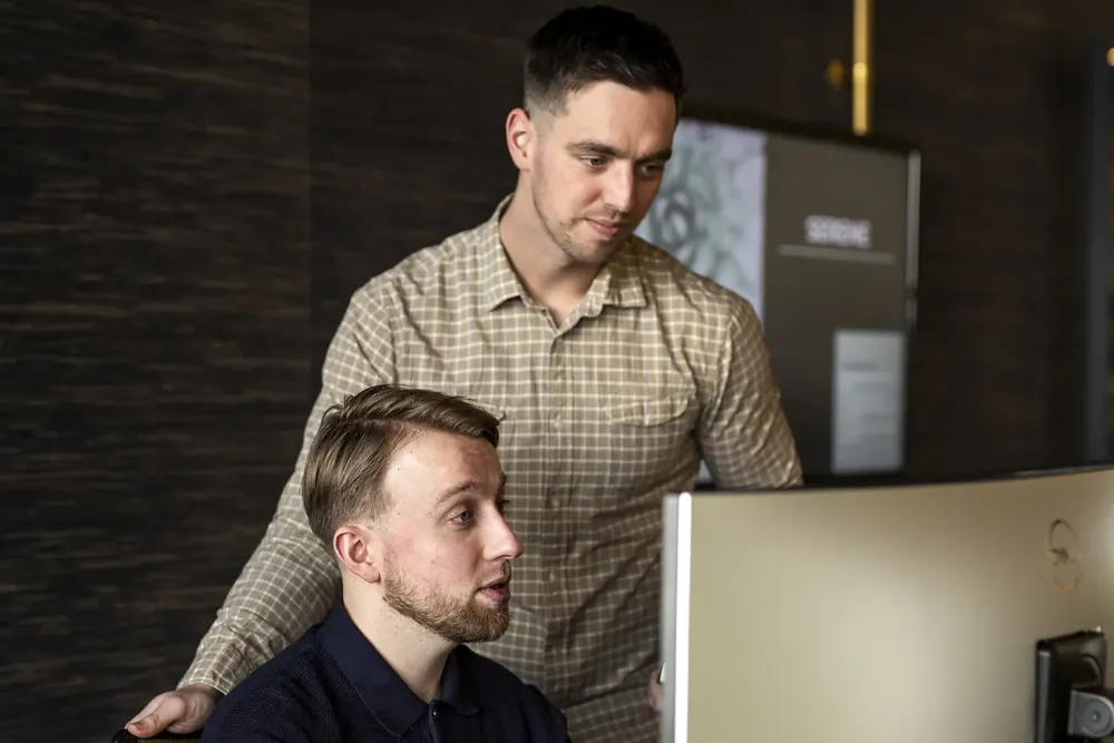 Twee collega's bekijken samen een beeldscherm