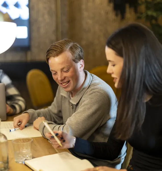 Twee collega's maken aantekeningen tijdens een overleg